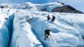 A group of climbers using ice picks to cross a glacier in Chile.